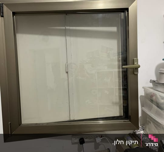 חלון עם תריסים סגורים ומסגרת מתכתית